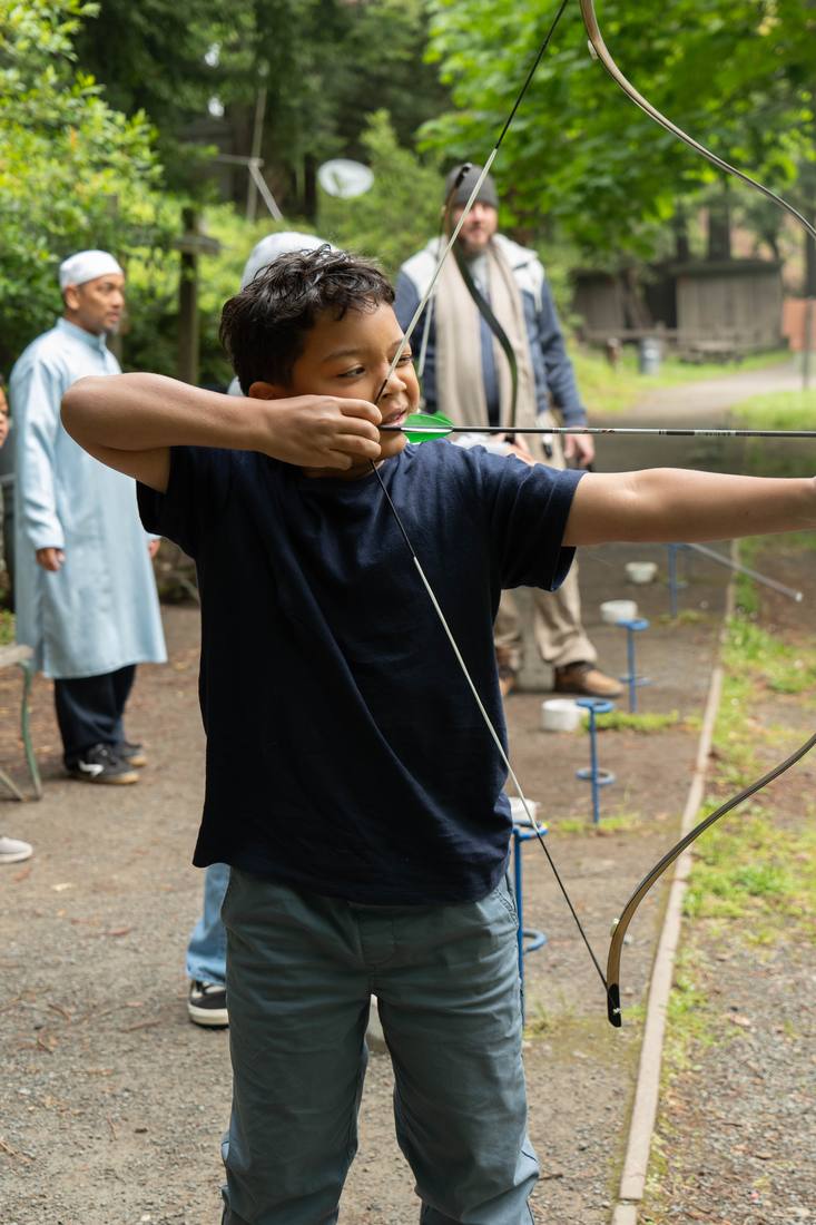 A student at full draw as an instructor watches closely