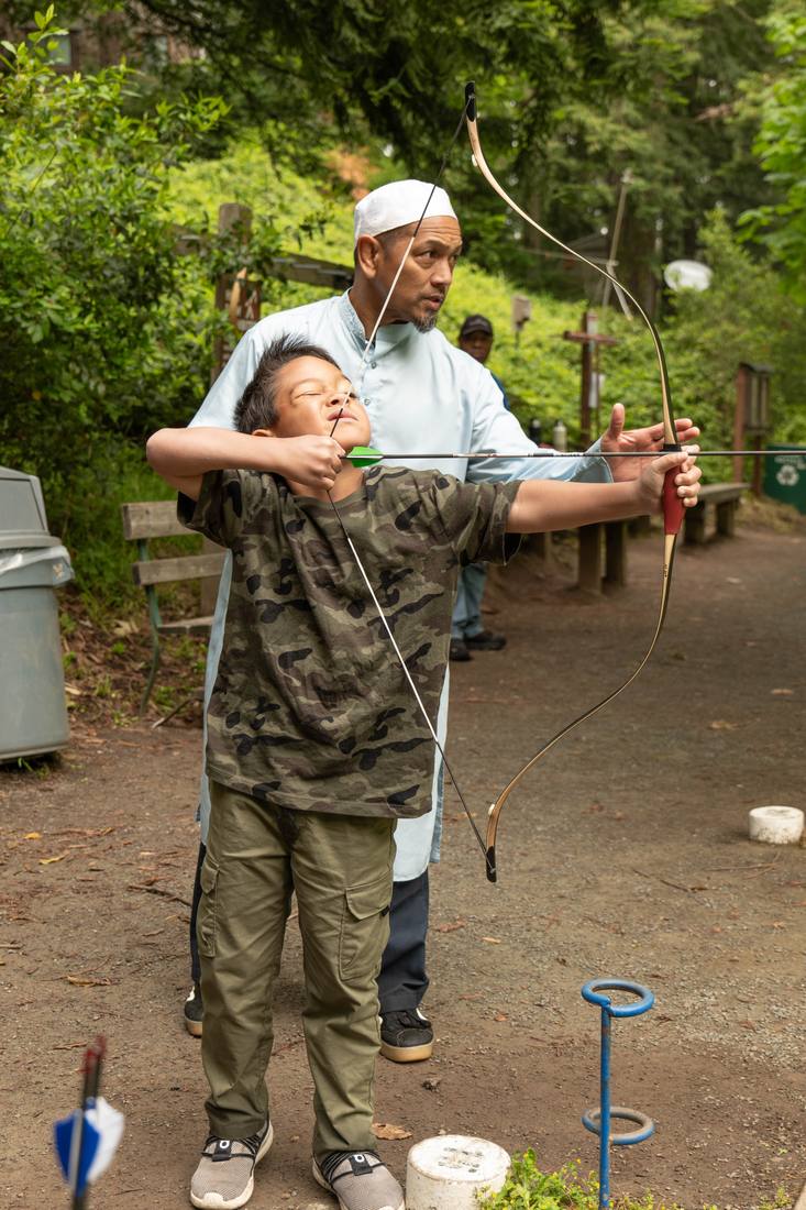 Hands-on archery coaching, adjusting a student's form