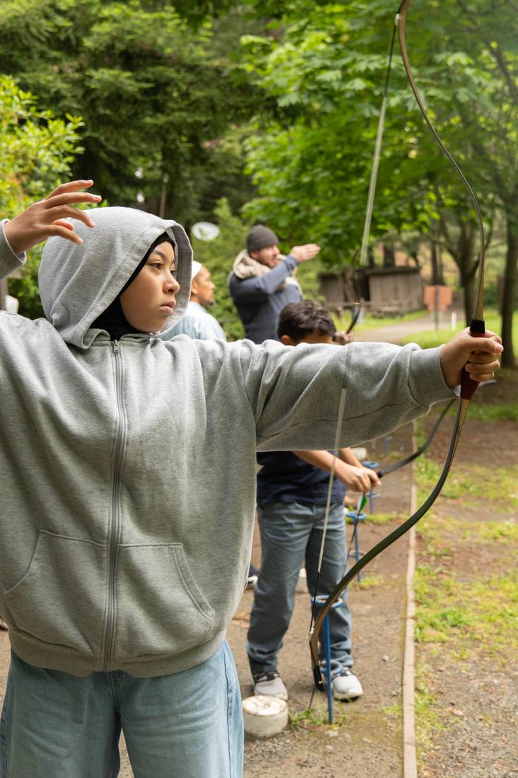 A young archer focused while drawing the bow